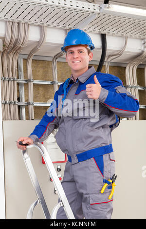 Young Worker Man With Hard Hat standing on ladder Stock Photo