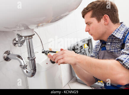 Portrait of male plumber fixing a sink in bathroom Stock Photo