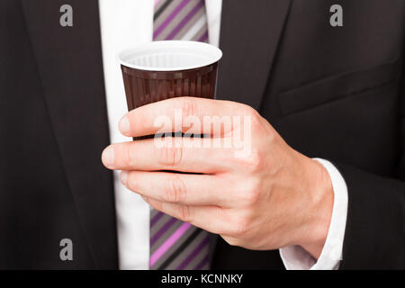 Portrait of happy businessman drinking coffee standing near vending machine Stock Photo