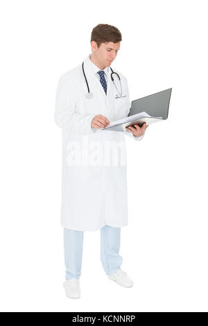 Young Male Doctor Checking Records Over White Background Stock Photo
