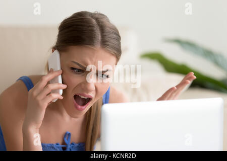 Angry dissatisfied young woman calling customer support or mobile banking, displeased client complaining about bad service, arguing on phone, having c Stock Photo