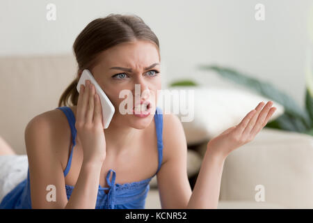 Angry young woman arguing talking on phone at home, dissatisfied girl calling customer service, having problem of conflict during telephone conversati Stock Photo