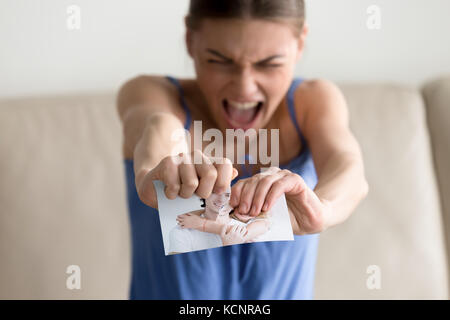Angry hysterical woman tearing photo of happy couple, erasing memories of ex-boyfriend after breaking up divorce, frustrated lovelorn teenager feeling Stock Photo