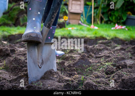 spades and rubber boots in the garden with green grass Stock Photo