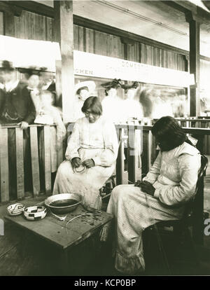 Effa Rhodes and Amy Enos, of the O'odham (Pima tribe) weaving baskets in the Domestic Science exhibit at the Model Indian School. Department of Anthropology, 1904 World's Fair Stock Photo