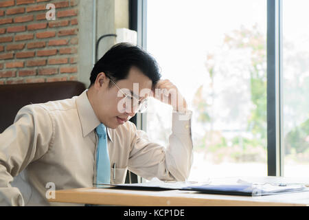 Asian businessman sitting and thinking in cafe, looking frustrated and depressed. Stock Photo
