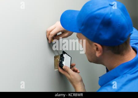 electrician installing light switch on the wall Stock Photo