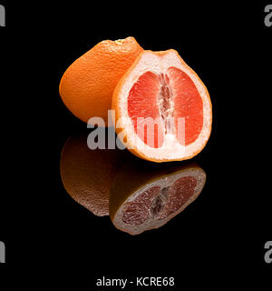 Half a grapefruit. On a black glossy background with real reflection. Stock Photo