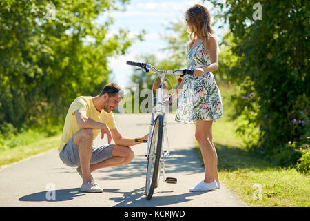 happy young couple fixing bicycle on country road Stock Photo