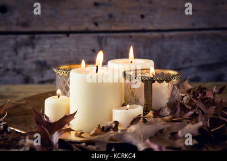 Close-up of lit candles and dry leaves on table Stock Photo