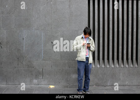 Man using his smart phone on a street in King's Cross, London Stock Photo