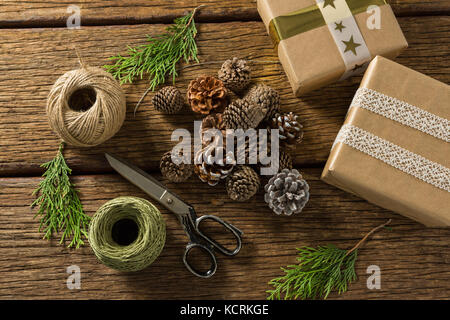 Overhead view of pine cones with gift boxes and thread spools on wooden table Stock Photo