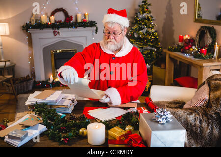 Santa Claus reading scroll in living room at home Stock Photo