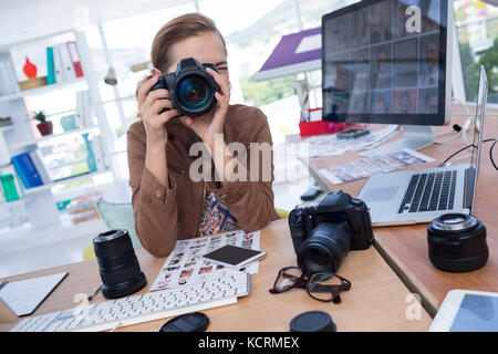 Female executive taking a photograph from digital camera in office Stock Photo