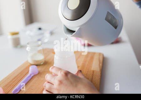 hands with kettle and bottle making baby milk Stock Photo