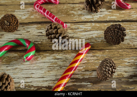 Candy canes and pine cones on weathered wooden plank Stock Photo