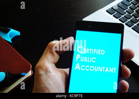 Hand holding phone with sign Certified public accountant (CPA). Stock Photo