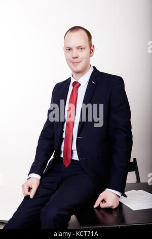 Doctor in a black suit standing and leaning on a table on a white background background. Stock Photo