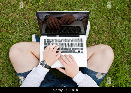 Businessman working with a laptop on the grass, green business and technology concept Stock Photo