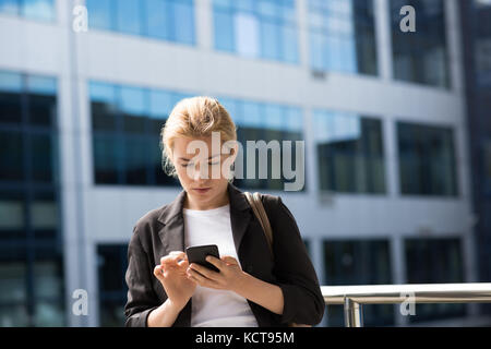 University student using mobile phone in campus at college Stock Photo