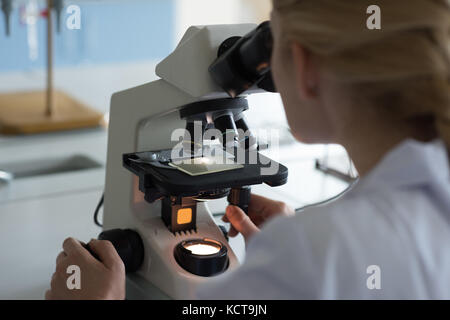 University student doing experiment on microscope in laboratory at college Stock Photo