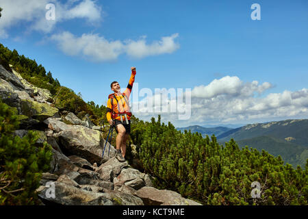 Hiker cheering elated and blissful with arms raised in the sky after hiking. Stock Photo