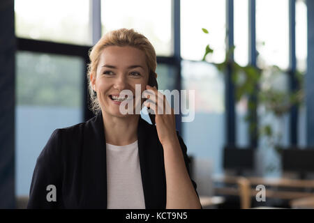 Smiling university talking on mobile phone in college Stock Photo