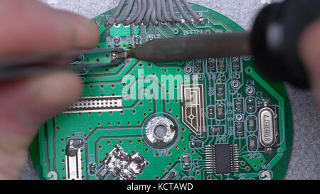 Microcircuit being fixed with soldering iron. Computer repair concept. Tweezers with chip and soldering Iron. soldering iron and microcircuit. microcircuit, microchip, integrated circuit Stock Photo