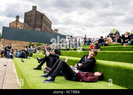 Young People enjoying the summer in Granary Square steps. Granary Square is a public square on the banks of Regent’s Canal   is the heart of King’s Cr Stock Photo