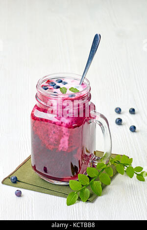 Jar of blueberry smoothie with berries and green leaves Stock Photo