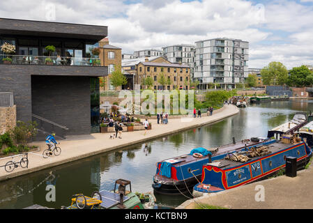 The canalside at Granary Square in the heart of King's Cross with people walking and barges on the canal. London, UK Stock Photo