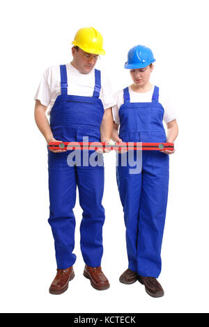 Male and female builders wearing yellow and blue helmet and blue overall checking spirit level indication - isolated on white background Stock Photo