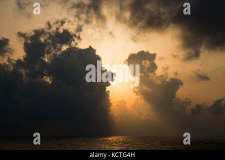 Bright Sun Shining Through Dark Clouds By The Sea Stock Photo