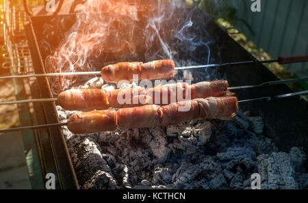 Sausages wrapped in bacon on the grill. Close. Selective focus. Stock Photo