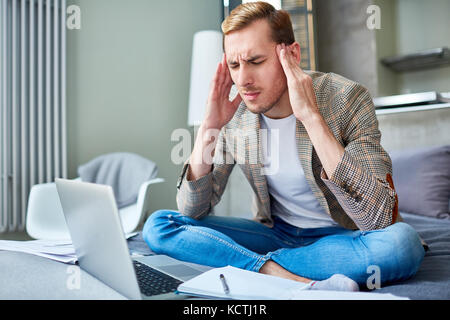 Young man touching his temples while suffering from headache Stock Photo