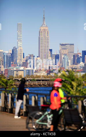 Visitors at Hudson River Waterfront Walkway in Liberty State Park with Midtown Manhattan NYC skyline and Empire State Building in background.NJ.USA Stock Photo