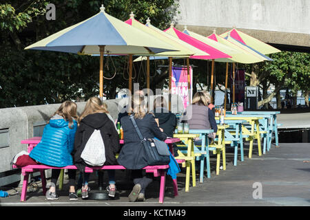 Garden umbrellas and tables outside the Wahaca restaurant and cafe at the South Bank Centre, London, UK
