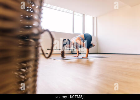 Woman standing on hands with feet lifted up doing crane yoga pose. fitness woman practicing Bakasana yoga pose in health center. Stock Photo