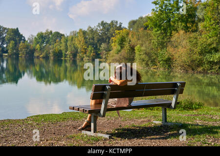 Woman in Munich, September 24, 2017 Woman in psychological crisis and depression sitting at a lake on September 24, 2017 in Munich, Germany. MODEL REL Stock Photo