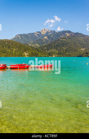 Red boats on transparent water of  alpine lake Wolfgangsee near St.Gilgen, Austria Stock Photo