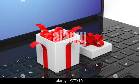 Open gift box full of Christmas balls on laptop keyboard. Stock Photo