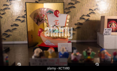 Colorfully painted clay figurines depicting ancient royal family members in elaborate gowns and headdresses shot through store window at night Stock Photo