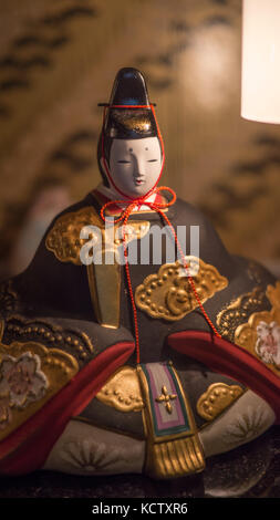 Colorfully painted clay figurines depicting ancient royal family members in elaborate gowns and headdresses shot through store window at night Stock Photo