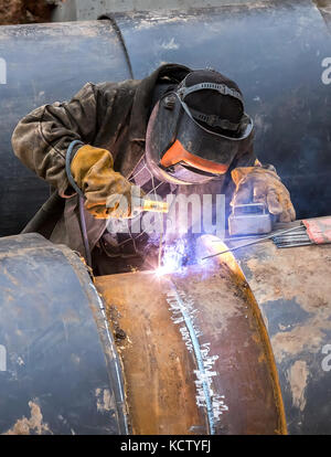 Worker with protective mask welding metal with sparks and smoke Stock Photo