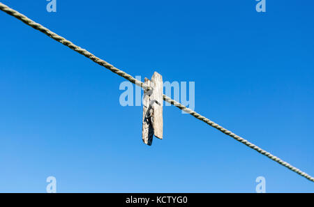Old wooden clothespin on the rope against the blue sky Stock Photo