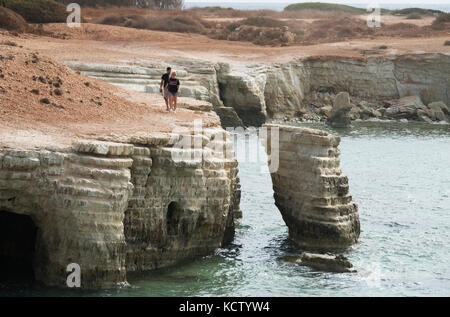 Two people walking along the cliffs at Sea caves near Peyia Paphos region, Cyprus. Stock Photo