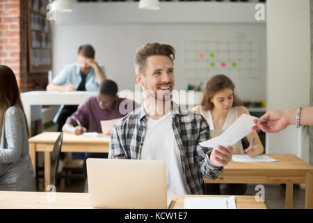 Smiling handsome entrepreneur giving financial document to coworker. Company employee happy to provide positive financial statistics to boss. Producti Stock Photo