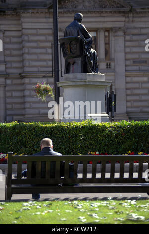 sitting om a bench watching life go by tourists George square Glasgow Stock Photo