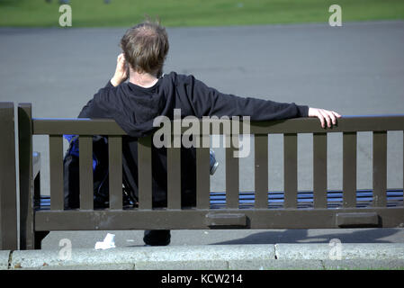 sitting om a bench watching life go by tourists George square Glasgow Stock Photo