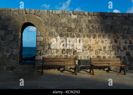 Vintage color tone style of wooden bench antique with sunrise by old city stone wall in Cefalu, Italy Stock Photo